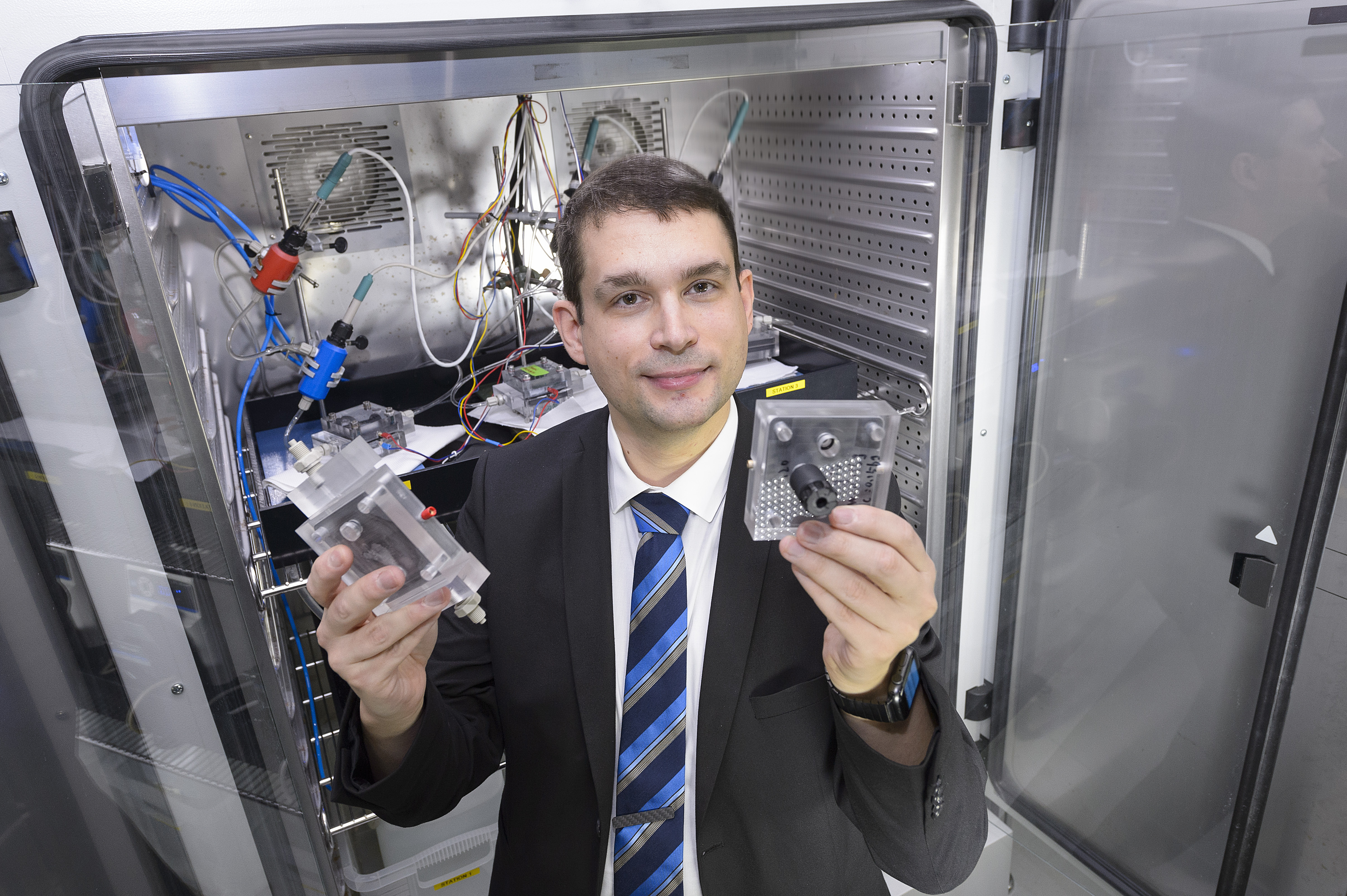 Professor zeigt Energiematerialien vor einer Laborapparatur