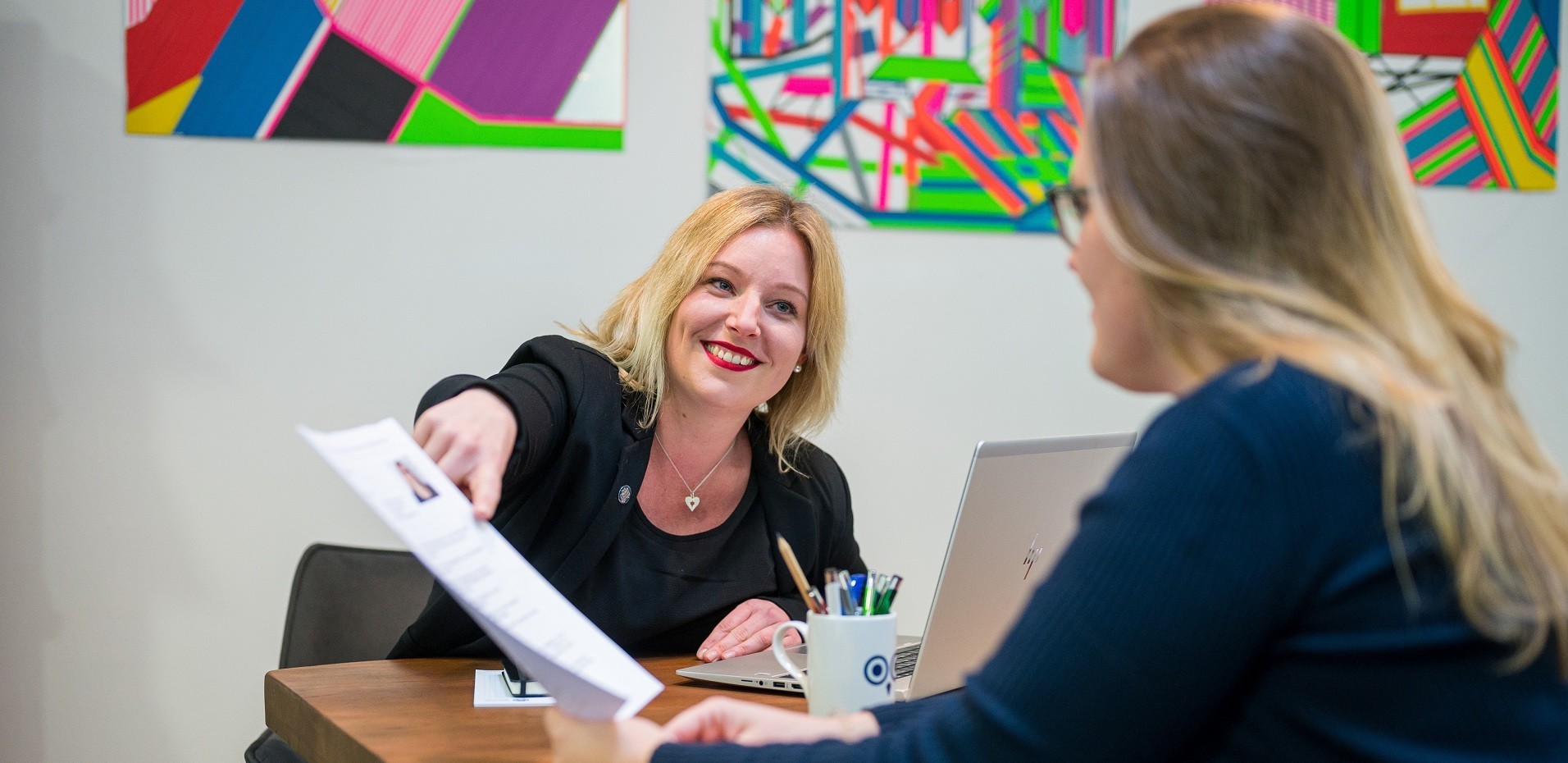 Zwei Frauen sprechen in einem Büro über ein Dokument