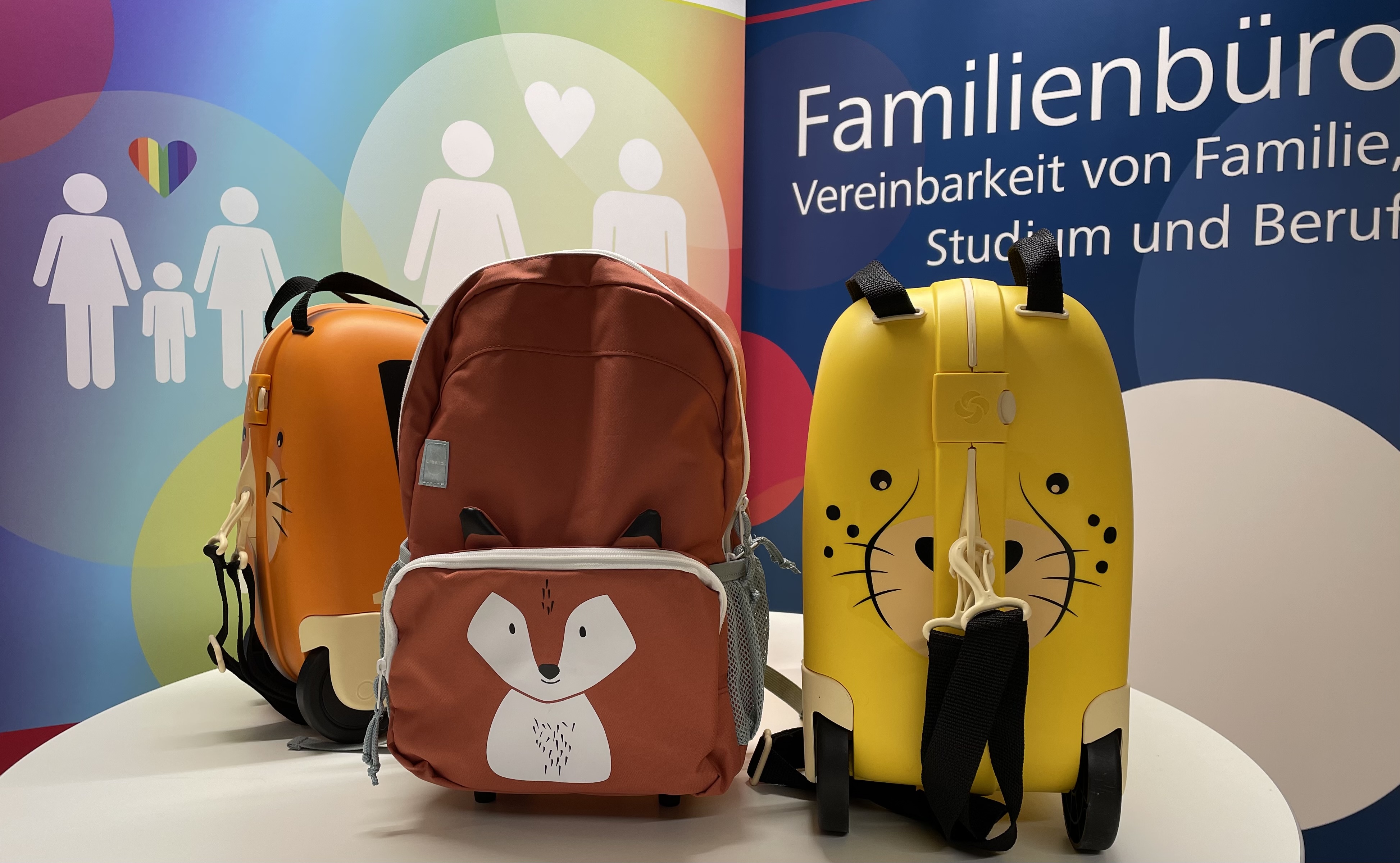 Die geschlossenen MoKis Tiger, Fuchs und Gepard auf einem Tisch vor Roll-Ups des Familienbüros